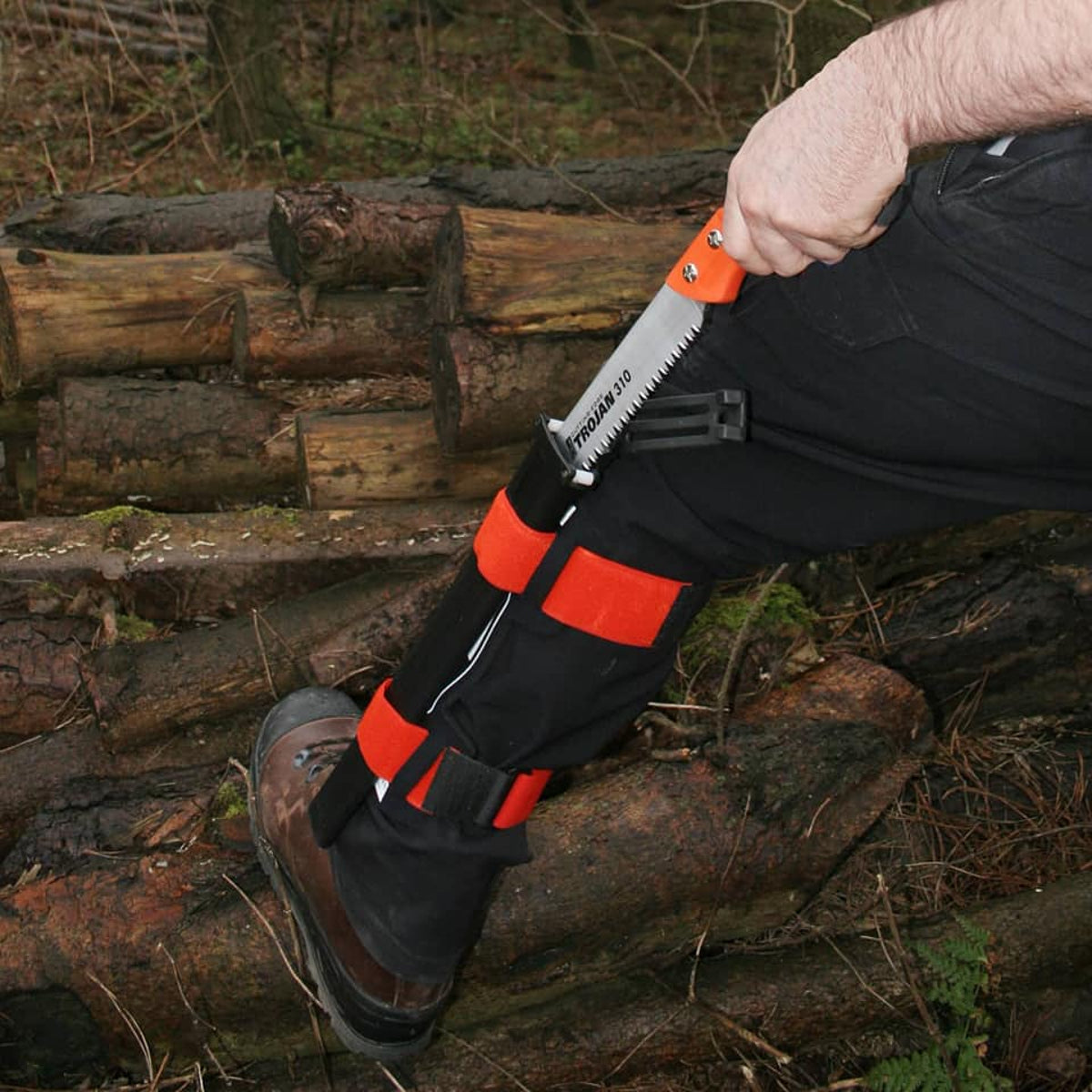 Person using a folding saw on a log with a forest background
