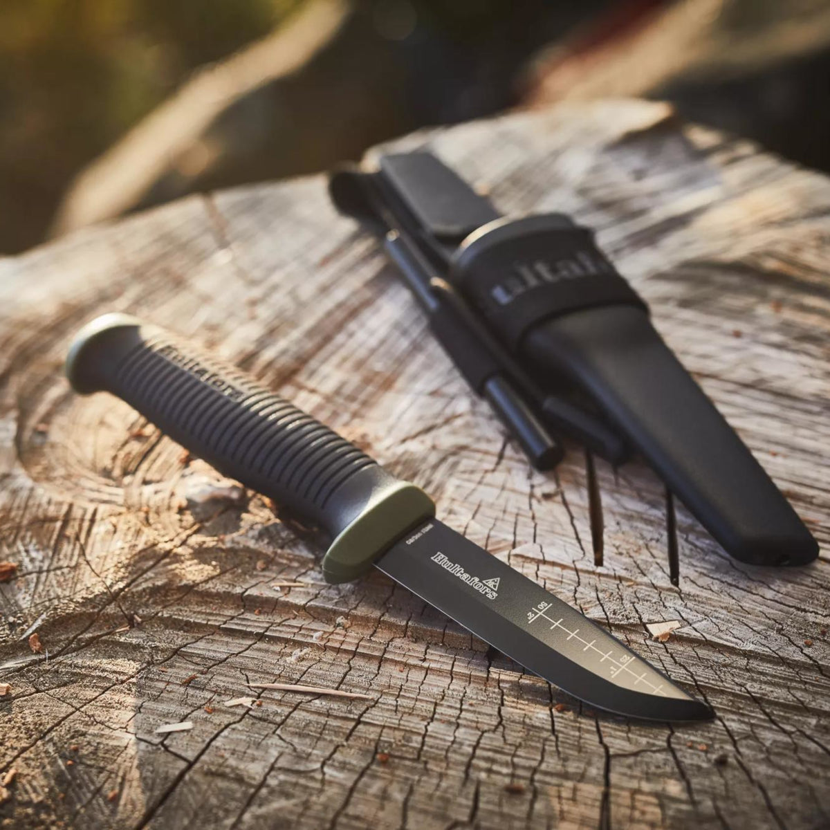 Black knife with sheath on a wooden surface