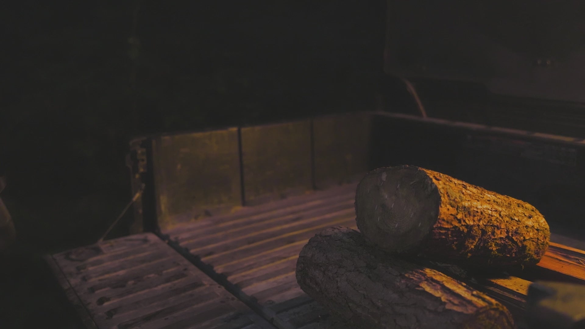 Video of a camping scene at night with a fire and chopping wood